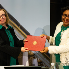 Two women both holding a red leather certificate folder