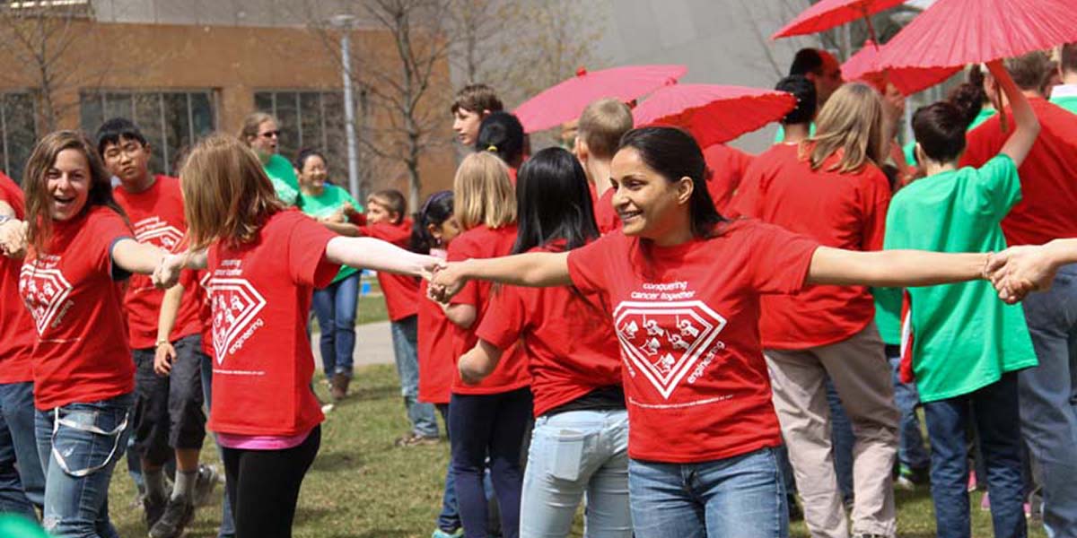 Young people in red shirts link hands