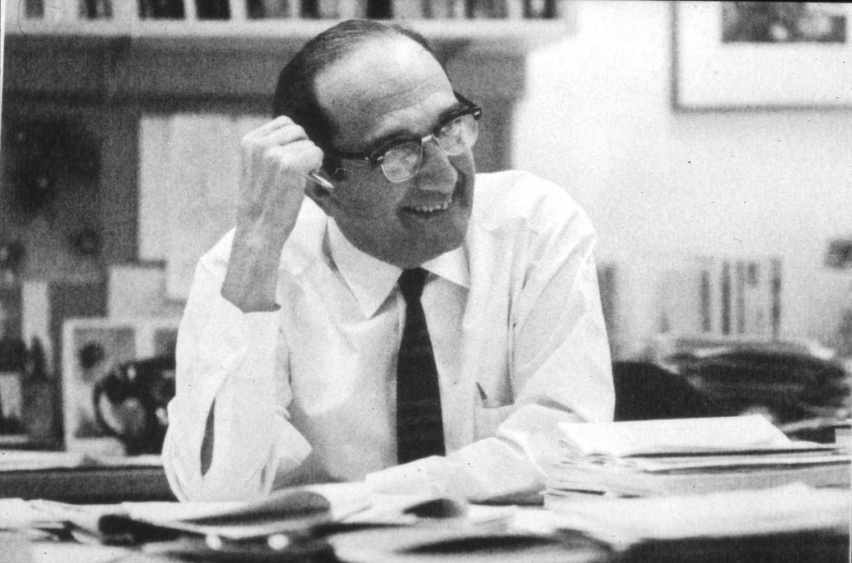 Salvador Luria at a desk, smiling