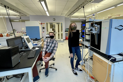 masked researchers standing near large lab machines